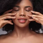 femme métissée au yeux fermés qui se touche le visage pour illustrer l'article qui traite de la definition glow